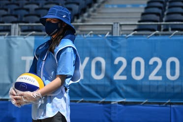 An attendant, wearing plastic gloves, holds a ball before the men's preliminary beach volleyball pool D match between Brazil and Argentina during the Tokyo 2020 Olympic Games at Shiokaze Park in Tokyo on July 24, 2021. (AFP)