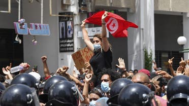 A Tunisian protester lifts a national flag at an anti-government rally as security forces block off the road in front of the Parliament in the capital Tunis on July 25, 2021. (AFP)