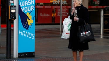 A woman smokes a cigarette as she stands by a sign encouraging people to wash their hands amid the outbreak of the coronavirus disease (COVID-19) in Belfast, Northern Ireland January 2, 2021. (Reuters)