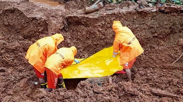 This handout photo taken on July 25, 2021 and released by India's National Disaster Response Force (NDRF), shows NDRF personnel recovering the body of a victim at the site of a landslide after heavy monsoon rains at Posare Khurd village in Khed district of Maharashtra. (AFP)