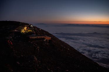 This photo taken on July 19, 2021 shows a line of lights (C) as people make their way up the trail to watch the sunrise from the summit of Mount Fuji, some 70 kilometres (43 miles) west of the capital Tokyo. (AFP)