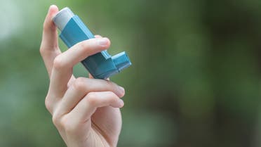 A picture of a man's hand holding a blue inhaler. (iStock)