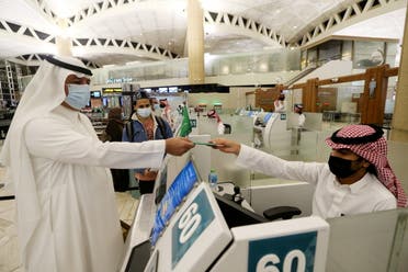 A Saudi man wearing a face mask gets his passport from a Saudi Immigration officer, at the King Khalid International Airport, in Riyadh, Saudi Arabia, May 16, 2021. (File photo: Reuters)