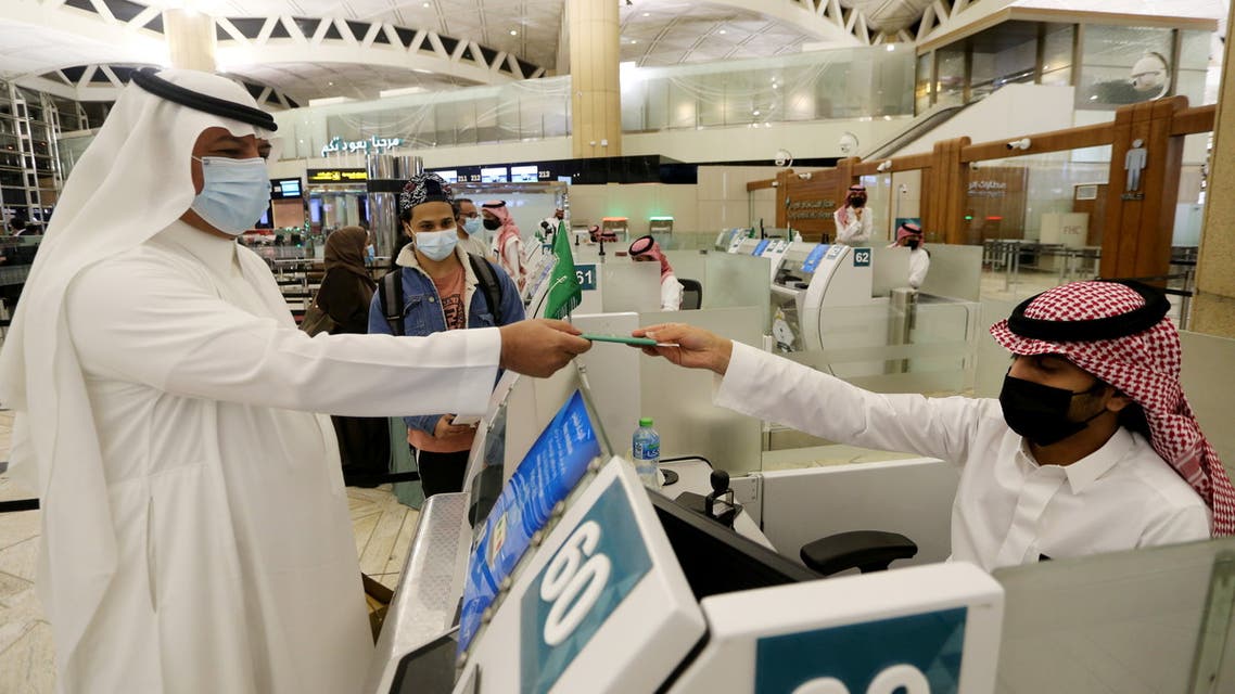 A Saudi man wearing a face mask gets his passport from a Saudi Immigration officer, at the King Khalid International Airport, after Saudi authorities lifted the travel ban on its citizens after fourteen months due to coronavirus disease (COVID-19) restrictions, in Riyadh, Saudi Arabia, May 16, 2021. (Reuters)