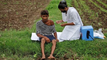 Healthcare worker Jankhana Prajapati gives a dose of the COVISHIELD vaccine against the coronavirus , manufactured by Serum Institute of India, to farmer Nareshbhai Dabhi in his field, during a door-to-door vaccination drive in Banaskantha district in the western state of Gujarat, India, on July 23, 2021. (Reuters)