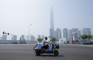 A man rides an electric motorcycle carrying water past Chow Tai Fook Financial Center in Tianjin's Binhai new district, China May 16, 2019. Picture taken May 16, 2019. (Reuters)