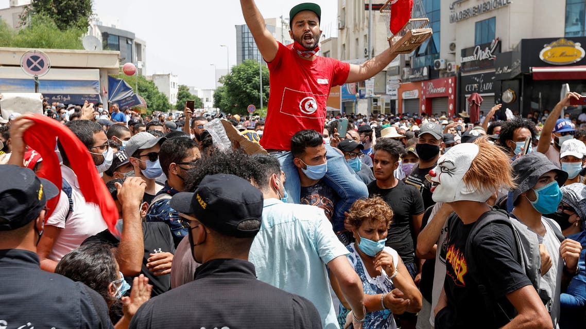 Demonstrators gather in front of police officers standing guard during an anti-government protest in Tunis, Tunisia, July 25, 2021. (Reuters)