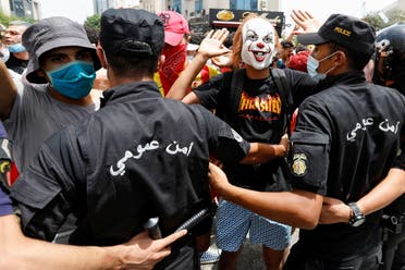A demonstrator wearing a mask gestures in front of police officers standing guard during an anti-government protest in Tunis, Tunisia, July 25, 2021. (Reuters)