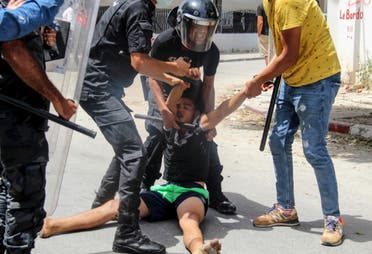 Tunisian police officers detain a protester during a demonstration in Tunis, Tunisia, Sunday, July 25, 2021. (AP)