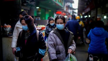 People wearing face masks walk on a street market, following an outbreak of the coronavirus in Wuhan, Hubei province, China, on February 8, 2021. (Reuters)