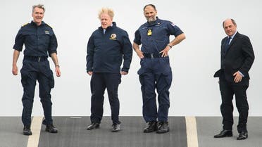 Prime Minister Boris Johnson, First Sea Lord Admiral Tony Radakin, Commodore Steve Moorhouse and Defence Secretary Ben Wallace face strong winds as they walk on the flight deck during a visit to HMS Queen Elizabeth aircraft carrier in Portsmouth, Britain, on May 21, 2021. (Reuters)