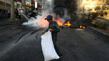 A Lebanese boy collects items from the street near tires set on fire during a protest at a main road in Lebanon's capital Beirut against dire living conditions amidst the ongoing economical and political crisis, on June 28, 2021. (File photo: AFP)