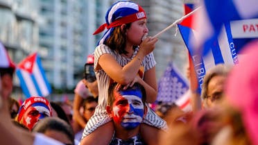 A girl sits on the shoulder of a man in reaction to reports of protests in Cuba against its deteriorating economy, in Miami, July 17, 2021. (Reuters)