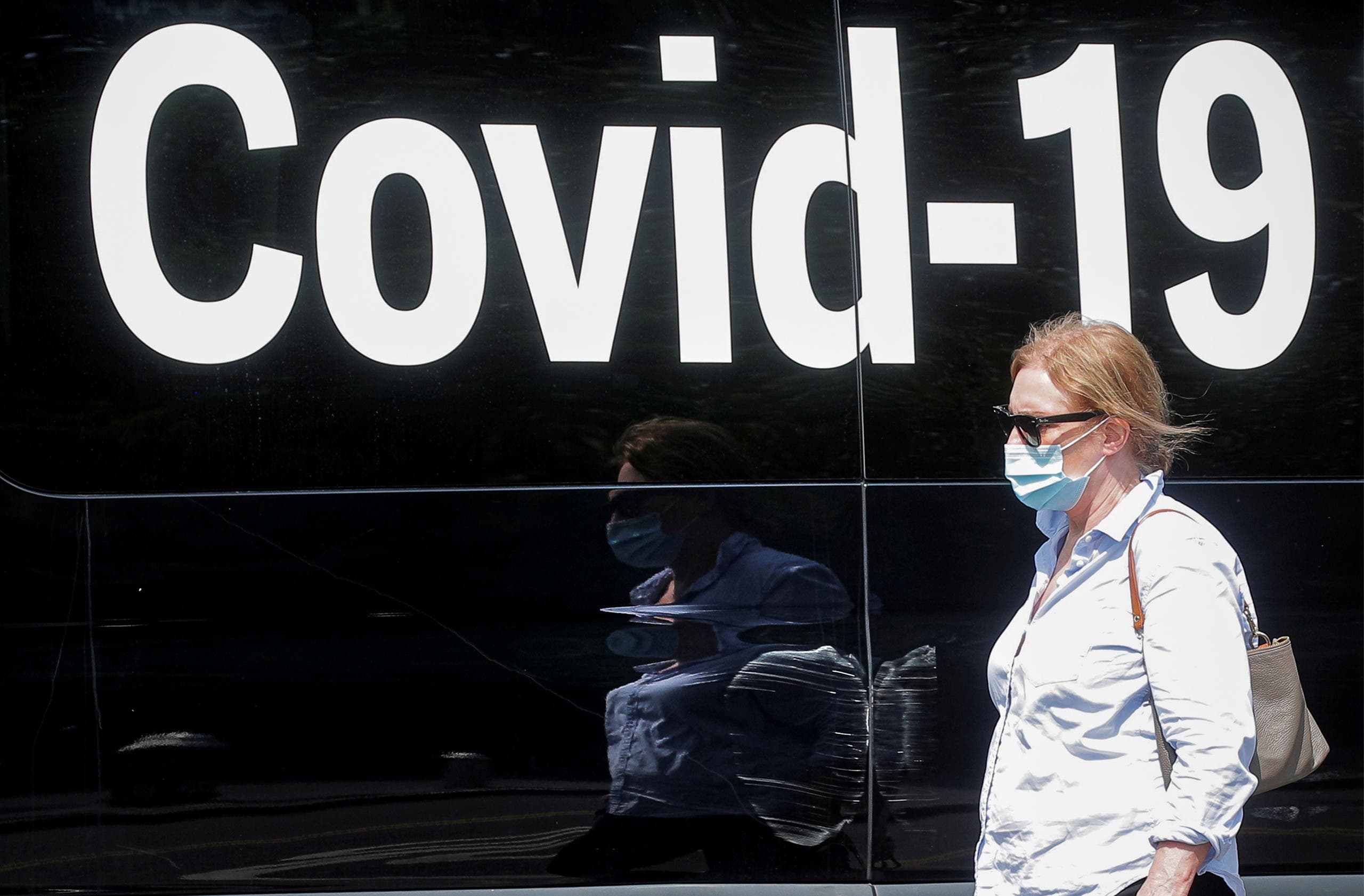 A woman wearing a mask passes by a coronavirus disease mobile testing van, as cases of the infectious Delta variant of COVID-19 continue to rise, in Washington Square Park in New York City, U.S., July 22, 2021. (Reuters)