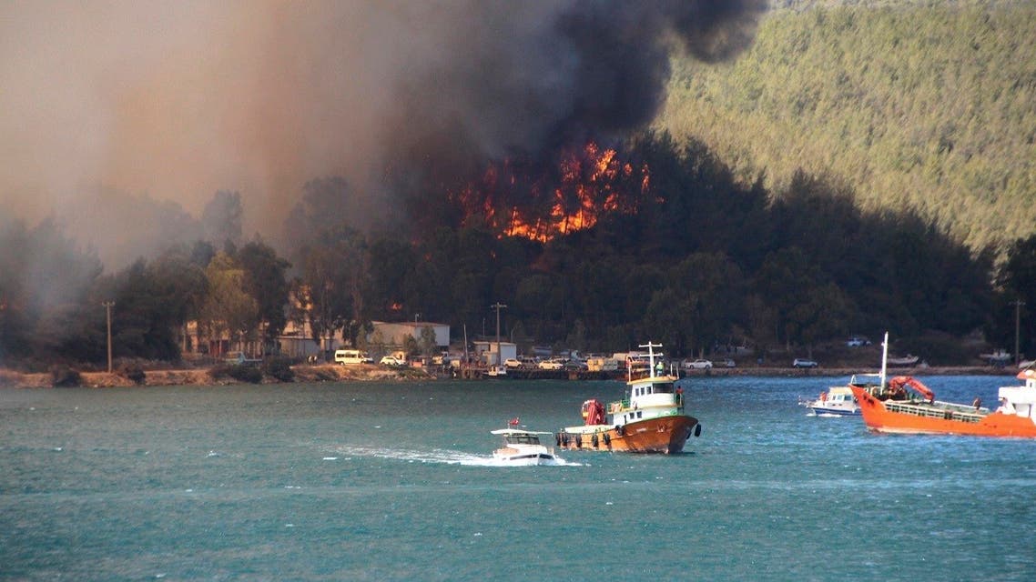 Smoke rises from a forest fire, threatening a residential area in the Aegean coastal town of Bodrum, Turkey, Thursday, July 29, 2021. (IHA via AP)