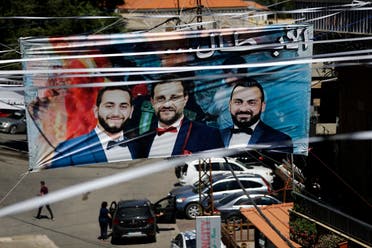 A banner bearing the portraits of firefighters Charbel Hitti, Charbel Karam, and Najib Hitti is seen hanging during their funeral procession in their hometown of Qartaba, north of the Lebanese capital Beirut, on August 17, 2020. (AFP)
