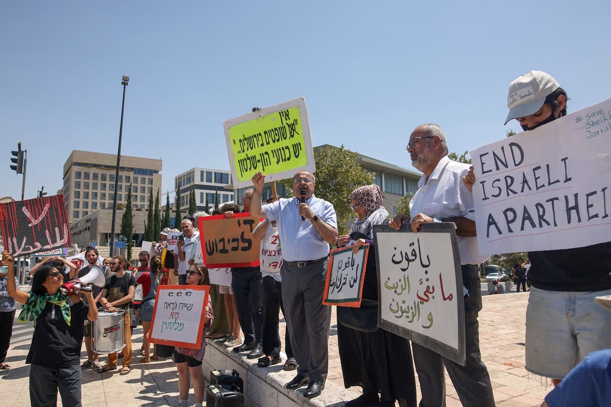 Arab Israeli Knesset member Ahmad al-Tibi (C) speaks as fellow MP Oussama al-Saadi lifts a banner, alongside Palestinian, Israeli, and foreign activists, during a demonstration outside the Supreme Court in Jerusalem, on August 2, 2021. (Ahmad Gharabli/AFP)