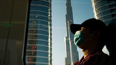 FILE - In this April 26, 2020 file photo, a commuter wearing a face mask to help curb the spread of the coronavirus, sleeps aboard the driverless Metro as it passes the Burj Khalifa, the world's tallest building, in Dubai, United Arab Emirates. After opening itself for New Year’s revelers, Dubai now find itself blamed by countries for spreading the coronavirus abroad. That's as questions swirl about the city-state’s ability to handle reported cases spiking to record levels. (File phoTo: AP)
