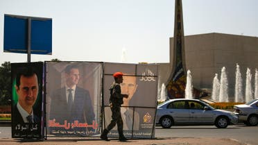 A Syrian military police officer walks past posters depicting Syria's President Bashar al-Assad, during the country's presidential elections in Damascus, Syria, May 26, 2021. (Reuters)