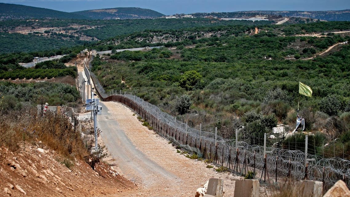 A Hezbollah flag flutters on the Lebanese side of the border fence with Israel, near the northern Israeli settlement of Shtula on July 20, 2021. Israel shelled Lebanon early today in response to earlier rocket attacks, the Israeli army said, as the United Nations urged all sides to show maximum restraint.