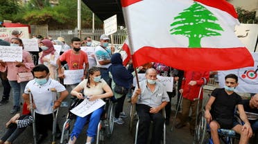 A man holds the Lebanese flag as he sits in a wheelchair during a protest demanding justice for victims of last year's Beirut port blast as Lebanon marks one year anniversary of Beirut port explosion on August 4, outside the Justice Palace in Beirut, Lebanon August 3, 2021. (Reuters)