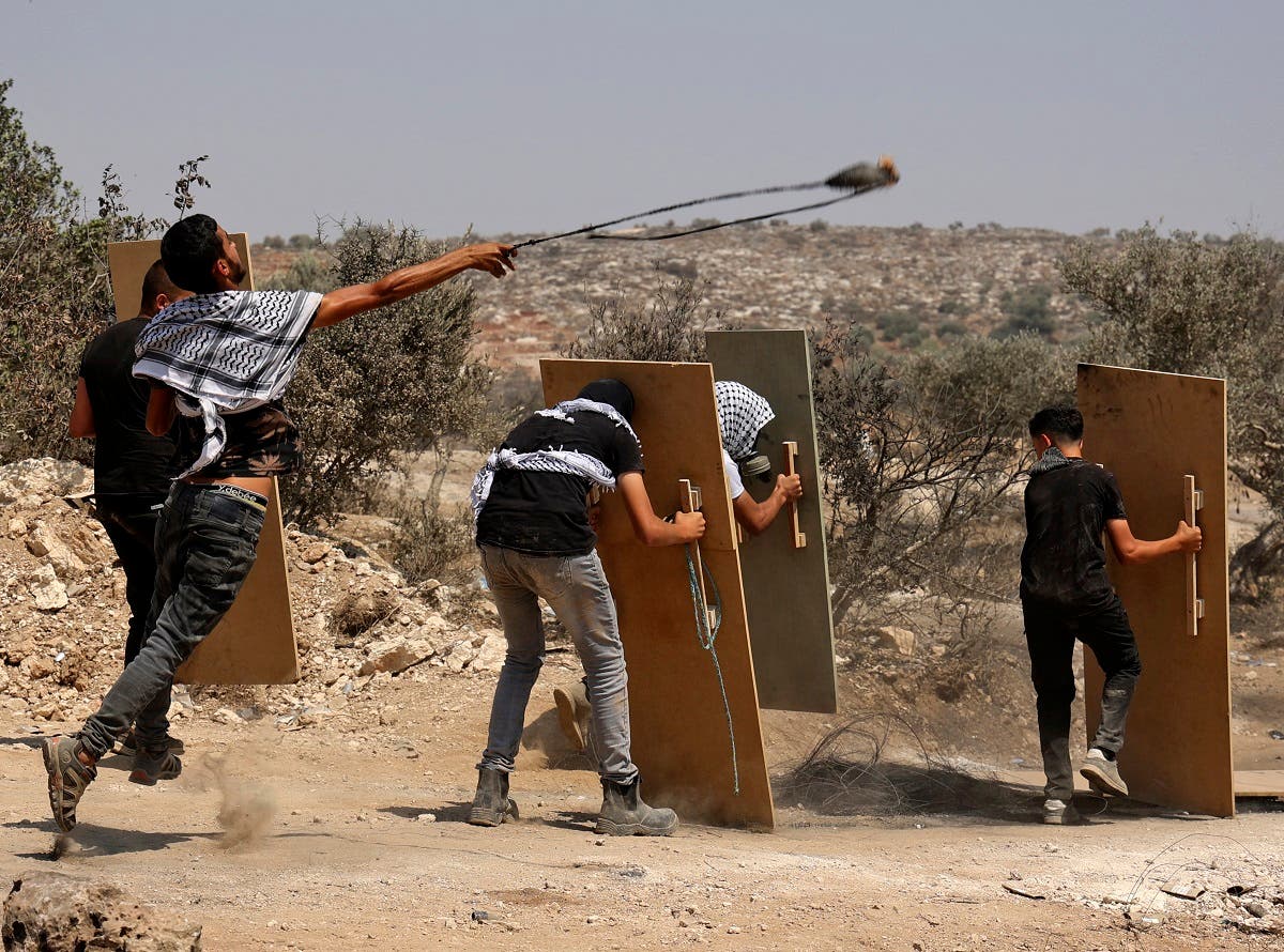 Palestinian protesters use wooden boards as shields amid clashes with Israeli forces during a demonstration against the Israeli outpost of Eviatar in the village of Beita, north of the occupied West Bank, on August 6, 2021. (Reuters)