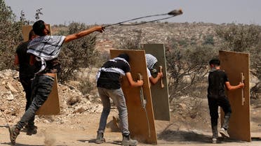 Palestinian protesters use wooden boards as shields amid clashes with Israeli forces during a demonstration against the Israeli outpost of Eviatar in the village of Beita, north of the occupied West Bank, on August 6, 2021. (Reuters)