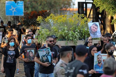 Families of the August 4 victims joined by protestors march with imitation coffins and portraits of their loved ones during a symbolic funeral procession from Beirut port on August 8, 2021, days after the first anniversary of a vast dockside explosion that left more than 200 people dead. (AFP)