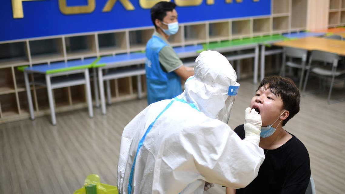 A medical worker in a protective suit collects a swab from a resident during a citywide nucleic acid testing following new cases of the coronavirus disease (COVID-19) in Wuhan, Hubei province, China, August 3, 2021. Picture taken August 3, 2021. REUTERS/Stringer CHINA OUT.