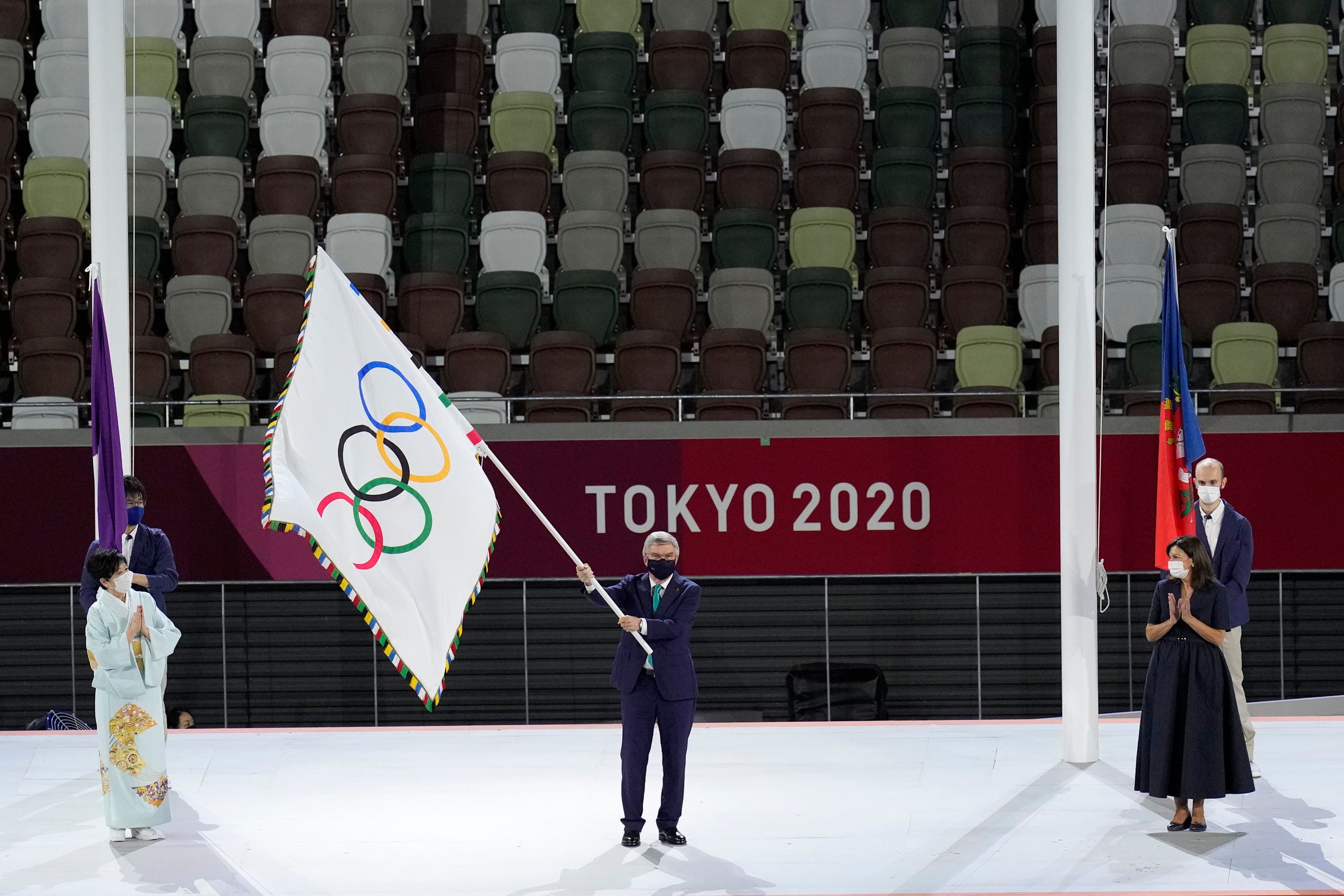 International Olympic Committee's President Thomas Bach waves the Olympic flag as Tokyo Gov. Yuriko Koike, left, and Paris mayor Anne Hidalgo, right, watch during the closing ceremony in the Olympic Stadium at the 2020 Summer Olympics, Sunday, Aug. 8, 2021, in Tokyo, Japan. (AP)