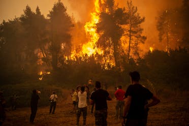 A local uses a megaphone as others observe a large forest fire approaching the village of Pefki on Evia (Euboea) island, Greece's second largest island, on August 8, 2021. (AFP)