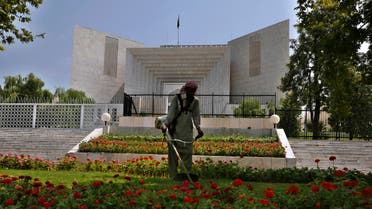 A worker mows the front lawn of the Supreme Court building where the hearing of the Hindu temple attack case is held in Islamabad, Pakistan, Friday, Aug. 6, 2021. (AP)