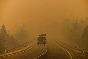 Cars drive down a road covered with smoke from nearby forest fires between the village of Magaras and the city of Yakutsk, in the republic of Sakha, Siberia, on July 27, 2021. (AFP)