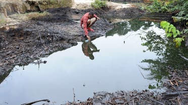 In this file photo taken on August 11, 2011 a man scoops spilled crude oil allegedly caused by Shell equipment failure floating at the bank of B-Dere waterways in Ogoniland, Rivers State. (Pius Utomi Ekpei/AFP)