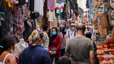 People wearing protective face masks walk past shops, amid the coronavirus disease (COVID-19) outbreak, in the Old City of Tunis, Tunisia, August 3, 2021. (Reuters)
