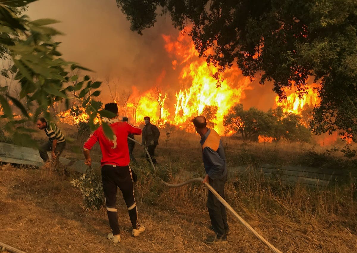 Villagers carry a hose as they try to put out a wildfire, in Achallam village, in the mountainous Kabylie region of Tizi Ouzou, east of Algiers, Algeria. (Reuters)