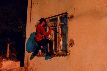 A youth breaks a window as men smash up shops and homes believed to be owned by Syrian families during an unrest, in Ankara, on August 12, 2021, overnight. (AFP)