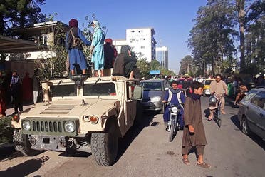 In this picture taken on August 13, 2021, Taliban fighters stand on a vehicle along the roadside in Herat, Afghanistan's third biggest city, after government forces pulled out the day before following weeks of being under siege. (AFP)