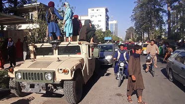 In this picture taken on August 13, 2021, Taliban fighters stand on a vehicle along the roadside in Herat, Afghanistan's third biggest city, after government forces pulled out the day before following weeks of being under siege.