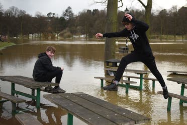 A youth leaps from a picnic bench in a flooded park in Shrewsbury, northwest England after Storm Christoph brought heavy rains and flooding across the country on January 22, 2021. (File photo: AFP)