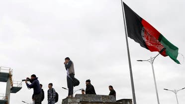 Youths take pictures next to an Afghan flag on a hilltop overlooking Kabul, Afghanistan, April 15, 2021. (Reuters)