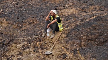 A volunteer rests after putting out a fire in the forested hills of the Kabylie region, east of the Algerian capital Algiers, on August 12, 2021. (Ryad Kramdi/AFP)