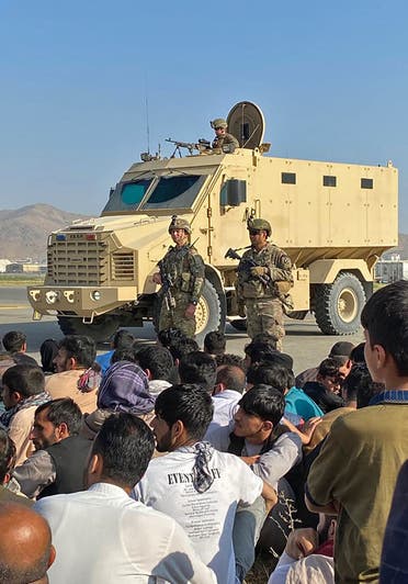 أفغان يحتشدون بالمطار في كابول بينما يقف جنود أميركيون (فرانس برس)