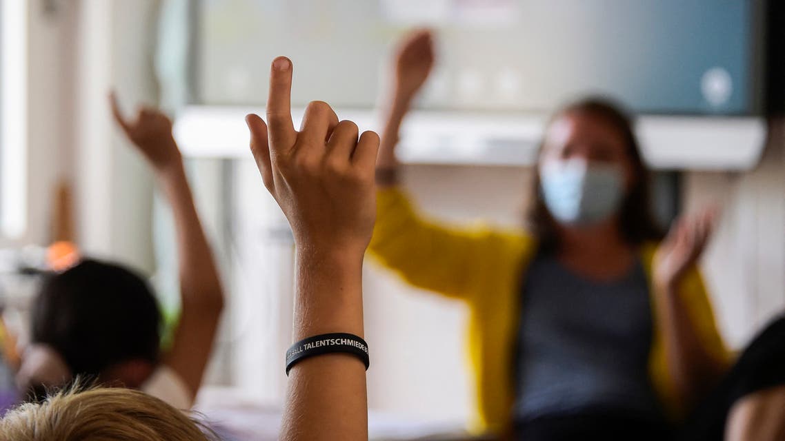 Pupils gesture towards their teacher as they attend a lesson at their elementary school in Berlin on August 9, 2021, after coming back from summer holidays and amid the coronavirus COVID-19 pandemic. (AFP)