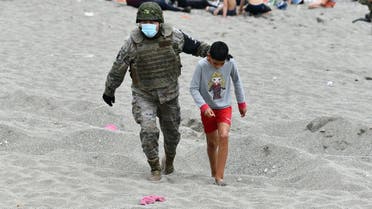A Spanish soldier walks with a migrant minor upon his arrival at the Spanish enclave of Ceuta, on May 18, 2021. (Antonio Sempere/AFP)