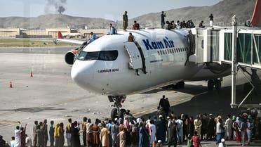 Afghan people climb atop a plane as they wait at the Kabul airport in Kabul on August 16, 2021. (AFP)