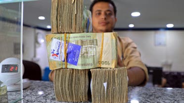An employee displays stacks of Yemeni riyal banknotes at a currency exchange office in Yemen's capital Sanaa on August 16, 2021