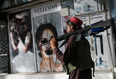 A Taliban fighter walks past a beauty salon with images of women defaced using spray paint in Shar-e-Naw in Kabul on August 18, 2021. (File photo: AFP)