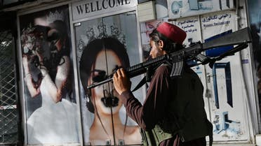 A Taliban fighter walks past a beauty salon with images of women defaced using spray paint in Shar-e-Naw in Kabul on August 18, 2021. (File photo: AFP)