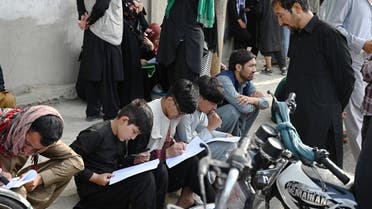 Afghan people fill up their details on a sheet of paper to register their name in order to leaves the country in front of the British and Canadian embassy in Kabul on August 19, 2021 after Taliban's military takeover of Afghanistan. (AFP)
